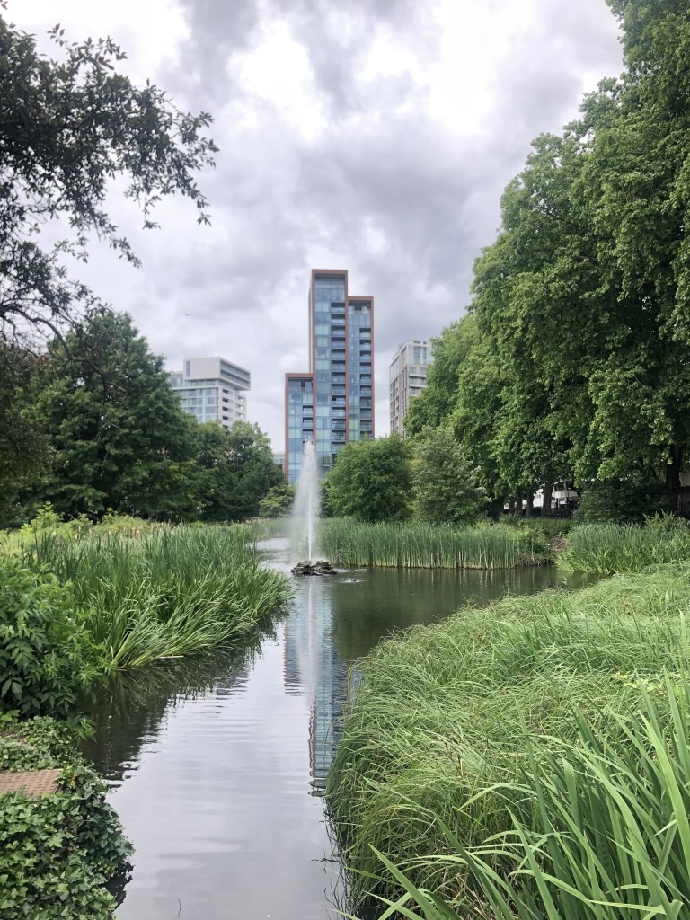 Going for a walk to tackle Eco-Anxiety in an urban landscape full of green areas, plants and a pond with a water fountain