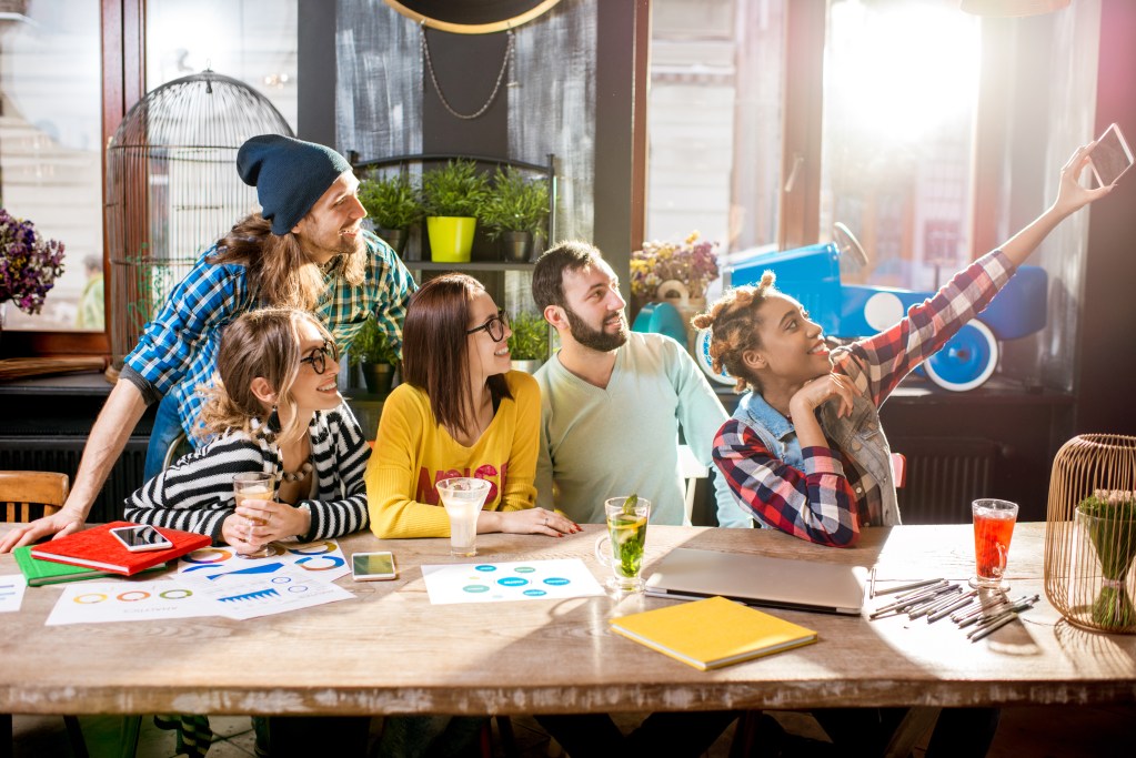 Group of young friends dressed casually making selfie photo sitting together in the modern cafe 