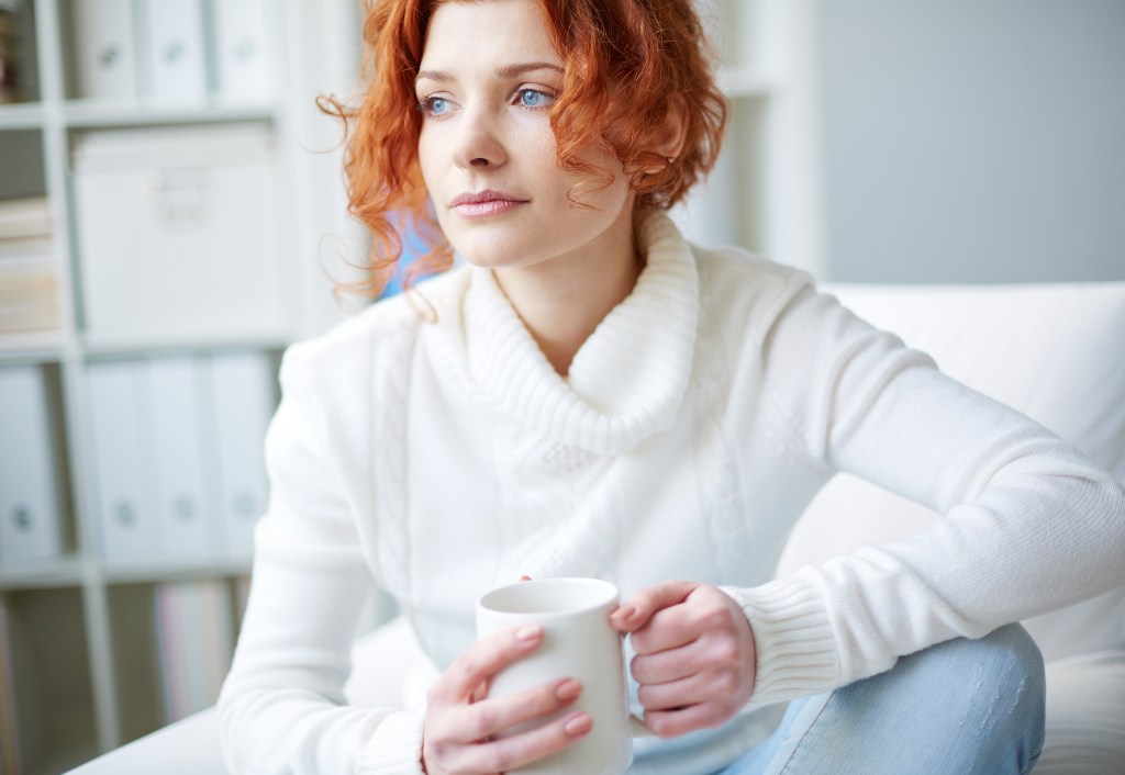 Woman with a white pullover and a cup of tea in her hand doing nothing of importance as a way to prevent burnout