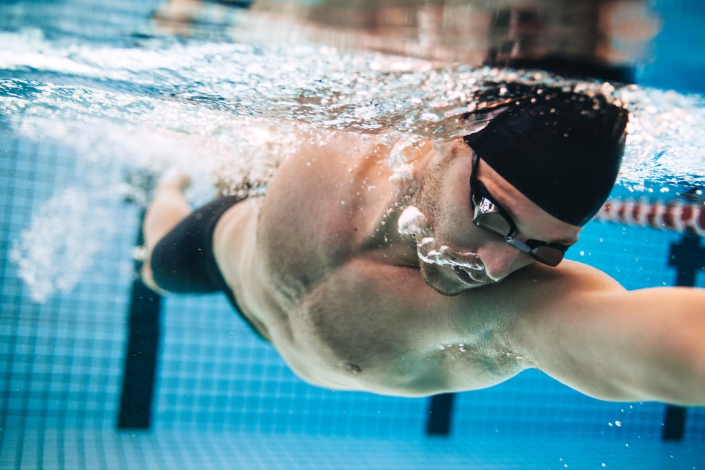 Professional male swimmer practising in a swimming pool