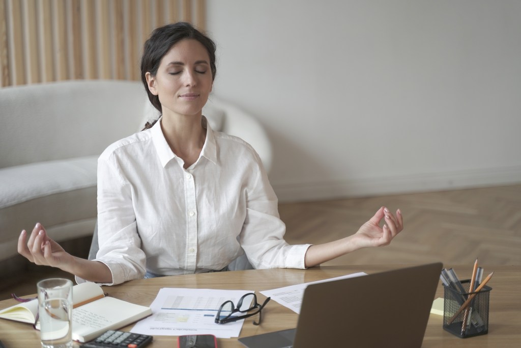 Female employee taking a short break at her desk to increase calm and mental readiness with a mindfulness practice.