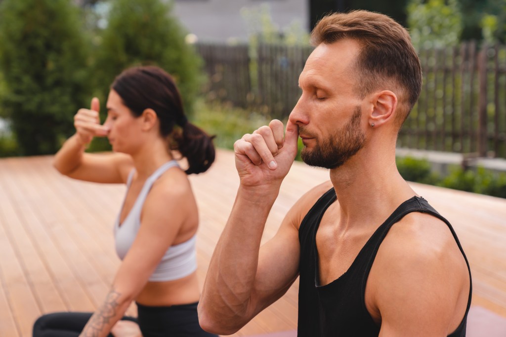 Two co-workers practicing alternative nostril breathing during an office break