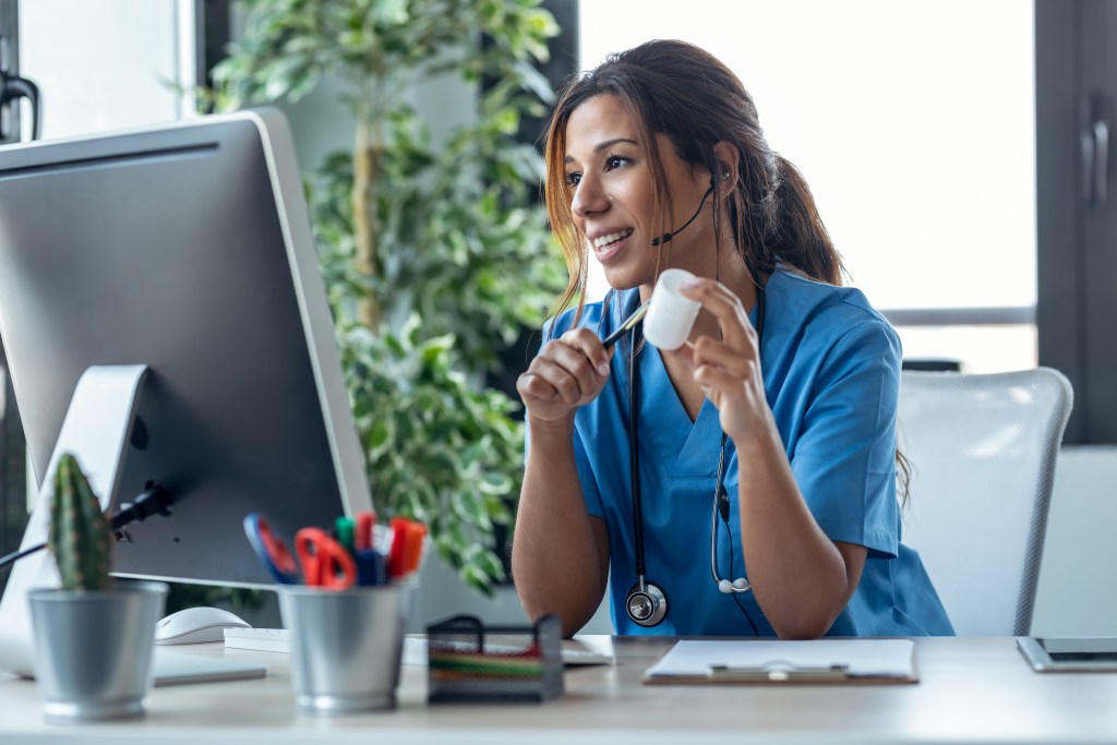 Female doctor talking with earphone while explaining medical treatment to patient through a video call with computer in the consultation.
Working from wherever she chooses has improved her mental health considerably.