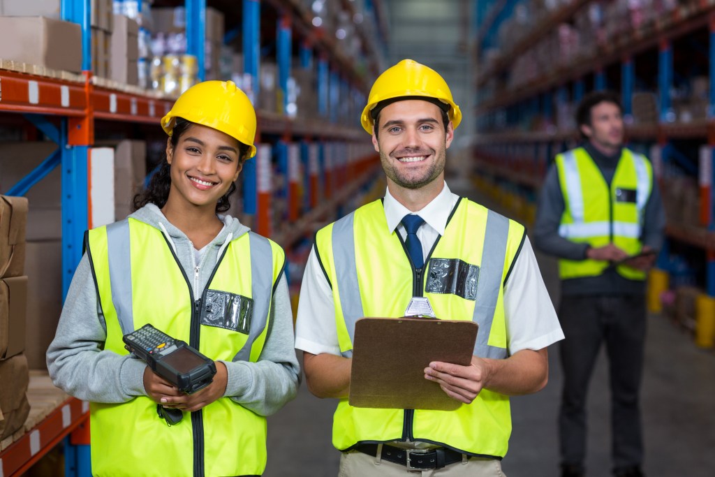 Two warehouse workers standing together in warehouse, ready to be their best selves at work