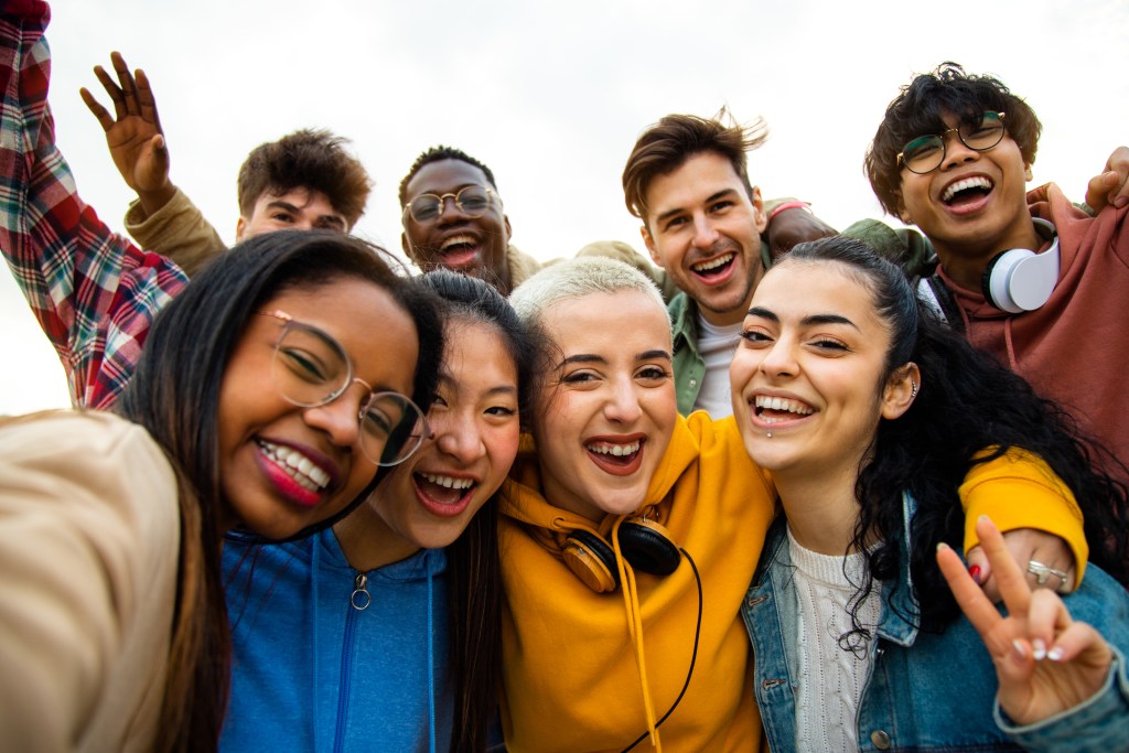 Group of eight teenagers, four male and four female, having fun outdoors, celebrating community and ready to shape the future.