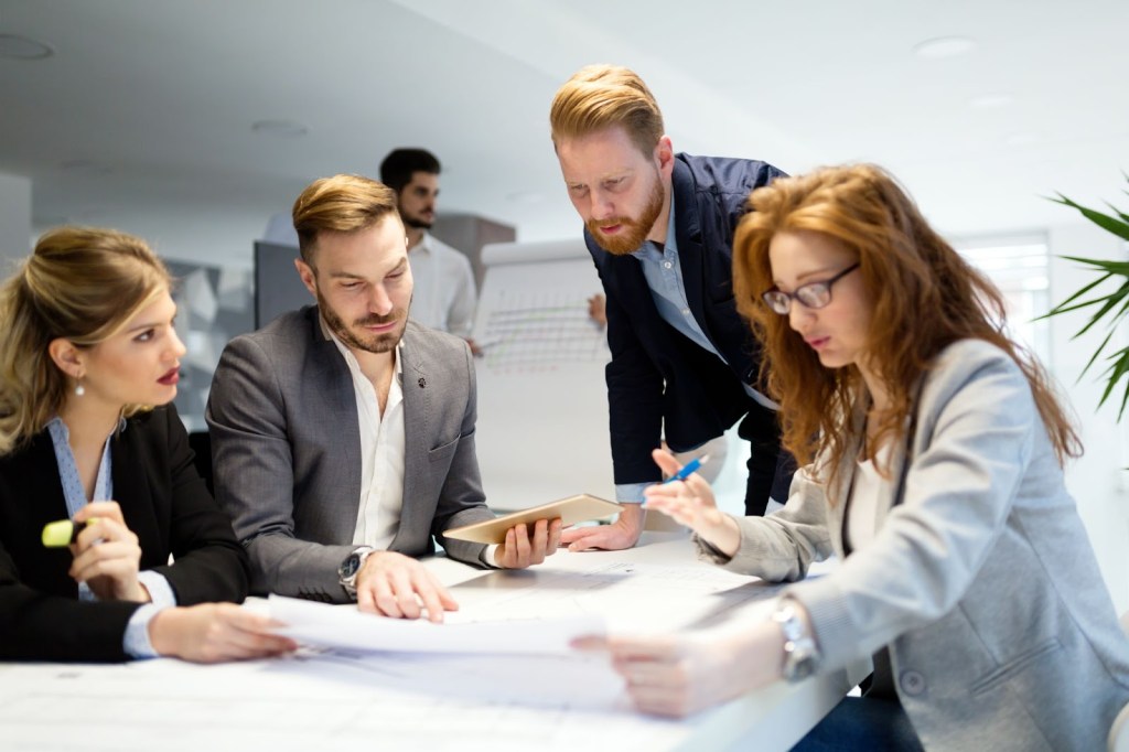 Classic perfectionist Ian explaining a marketing campaign roll-out in detail to his two female colleagues and his male project manager