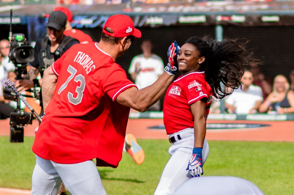 Mental health advocate and journaling fan Simone Biles at the 2019 All-Star Legends & Celebrity Softball Game 
giving Joe Thomas a high five