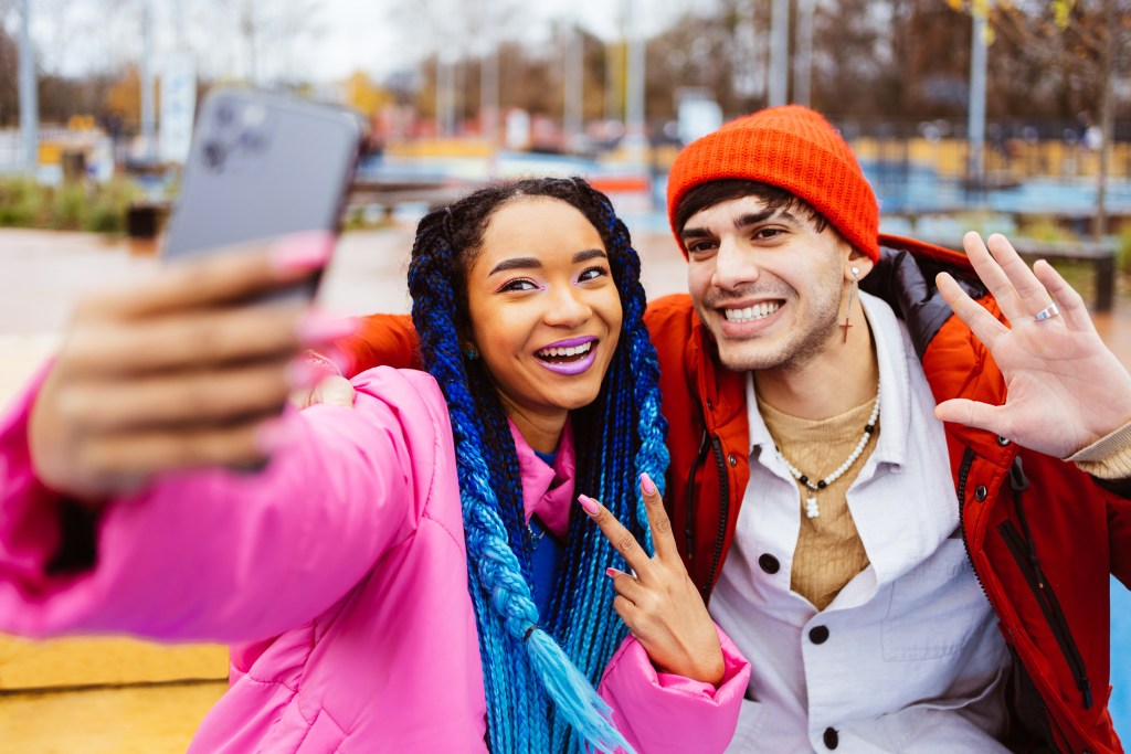 Affected by potential TikTok ban: Fashionable female African American and male Caucasian creators recording a video with their smartphone.