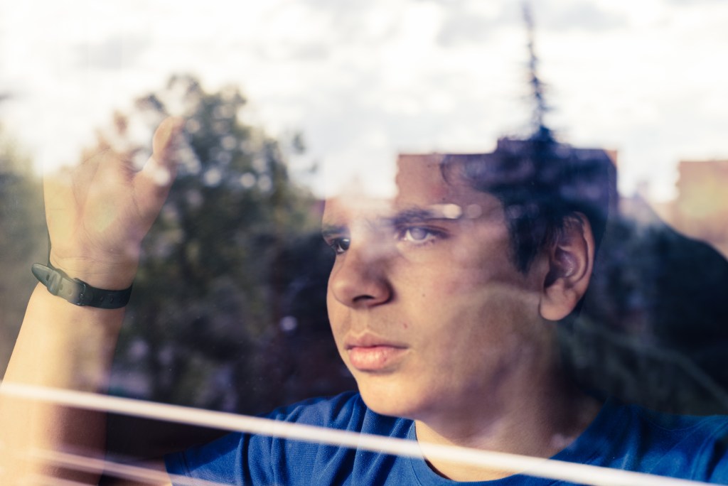 Sunday Scaries: Young man looking out the window worrying about the upcoming workweek