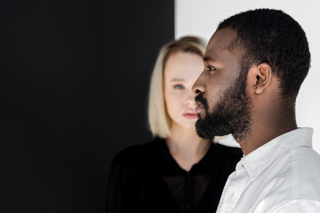 Emotional unavailability: side view of a man standing in front of a woman. Both disconnected