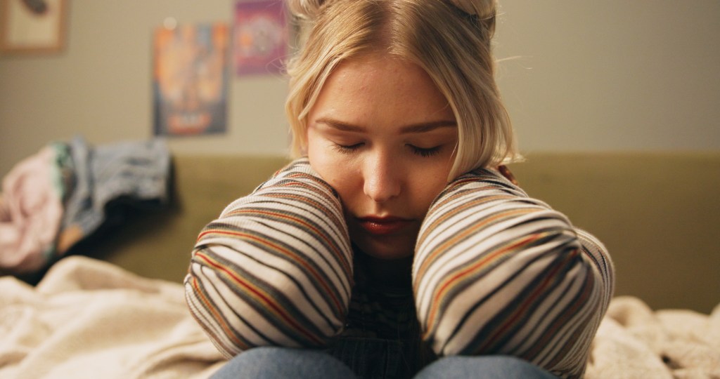 Young professional trying to figure out how to deal with rejections piling up in her life. She sits in her room, looking lost and hopeless.