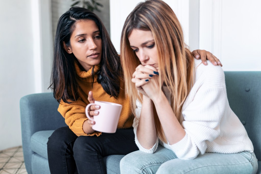 Shot of woman supporting and comforting her friend who is a new mom, while sitting on the sofa at home.