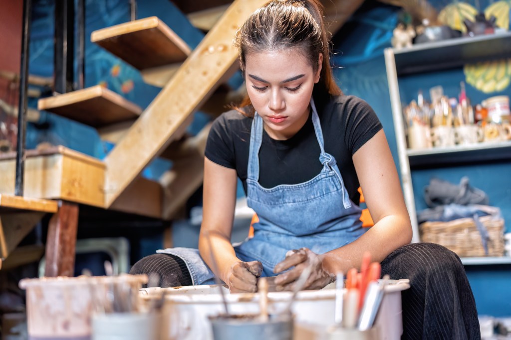 Woman making ceramic clay objects in pottery workshop. Since picking up that hobby she no longer struggles with the question "Why Do I Shut Down When Upset?"