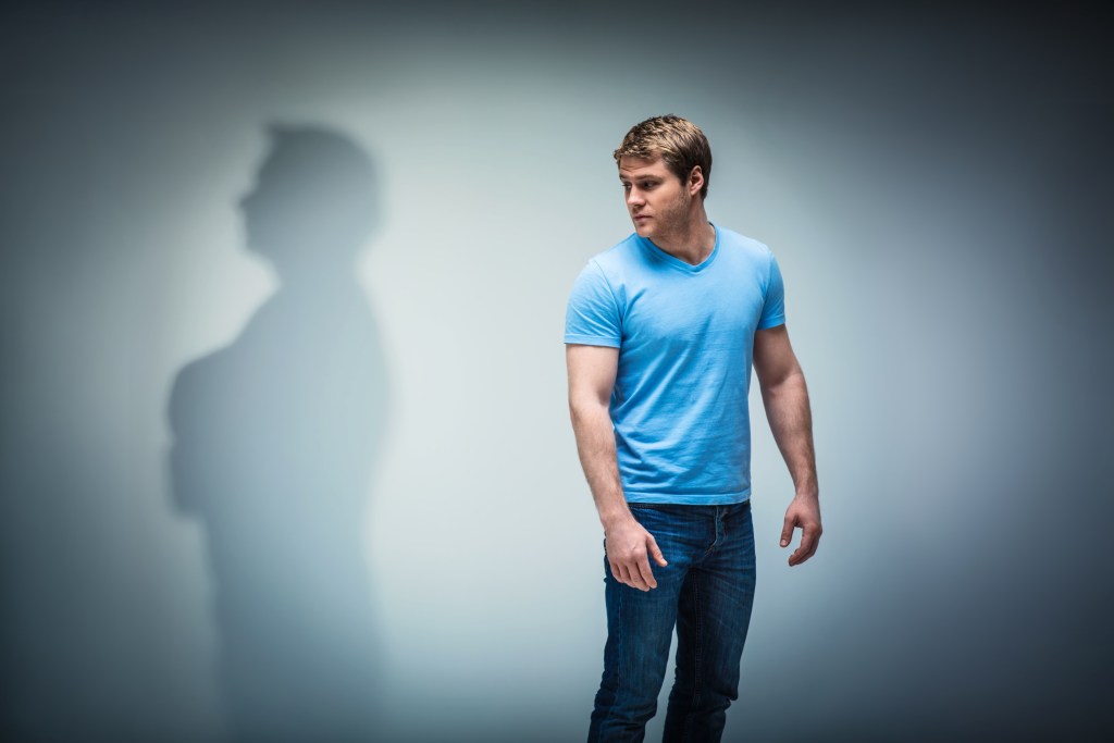 What is emotional safety within yourself? Young man looking at his rejective shadow