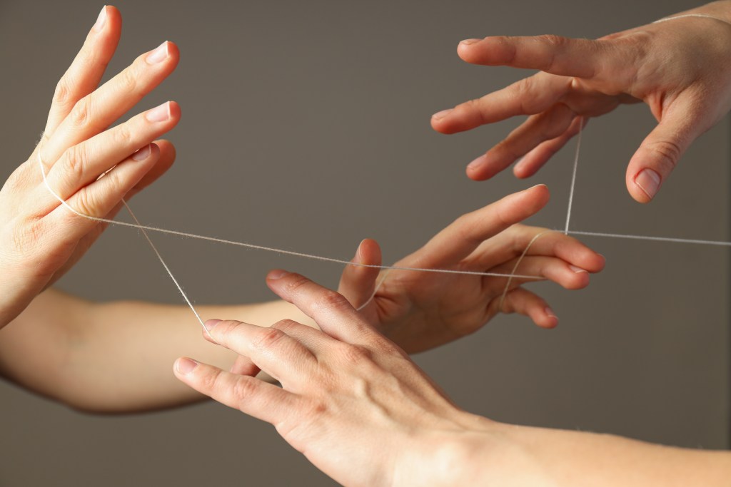 What is a trauma bond? Closeup of two pairs of hands entangled in a thread