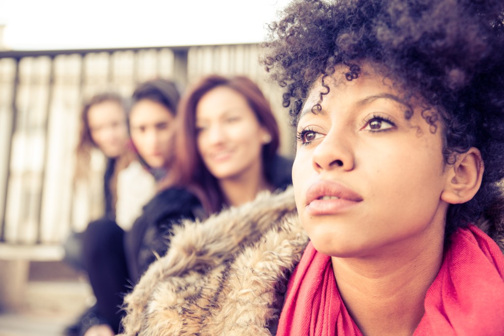 How to deal with fake friends: Woman walking away from fake friends smiling in the background