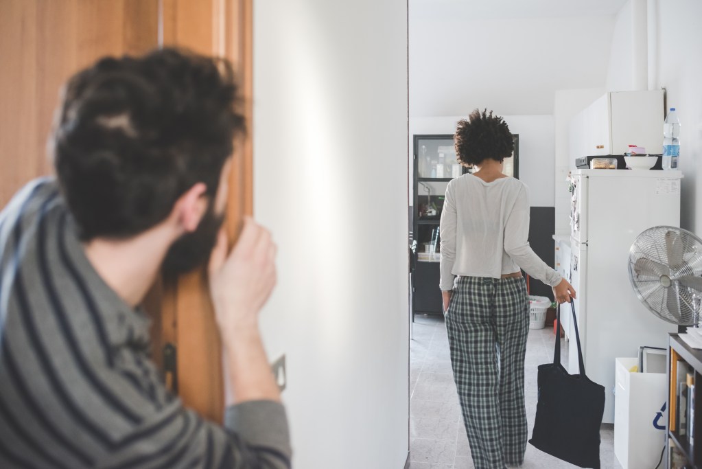 How to stop overthinking after being cheated on: Man indoor watching woman leaving