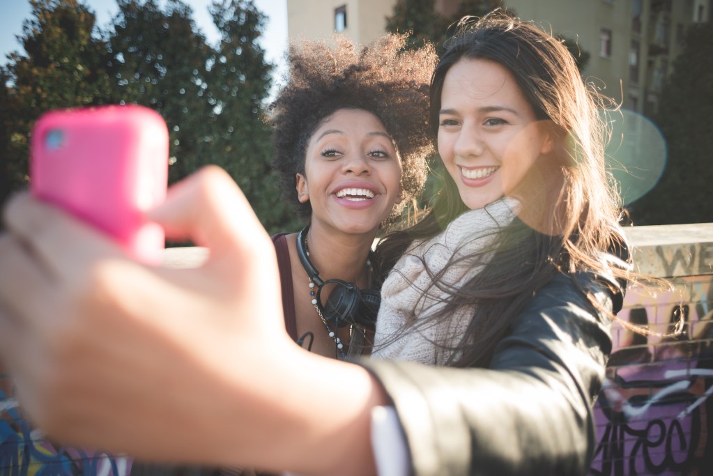 Codependent friendship can start quietly: Friends having fun taking selfie in town