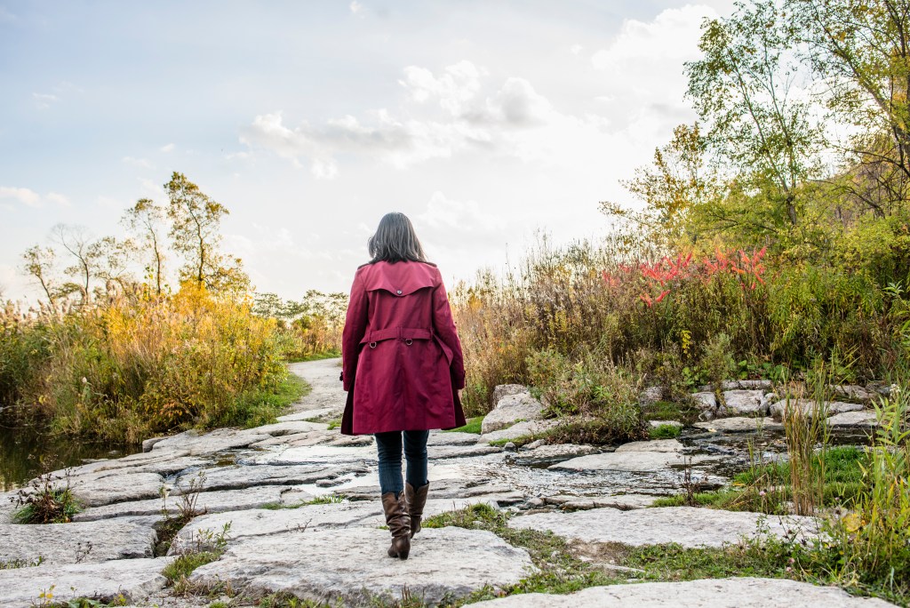 Self awareness: Rear view of woman walking on rocks, reflecting and processing 