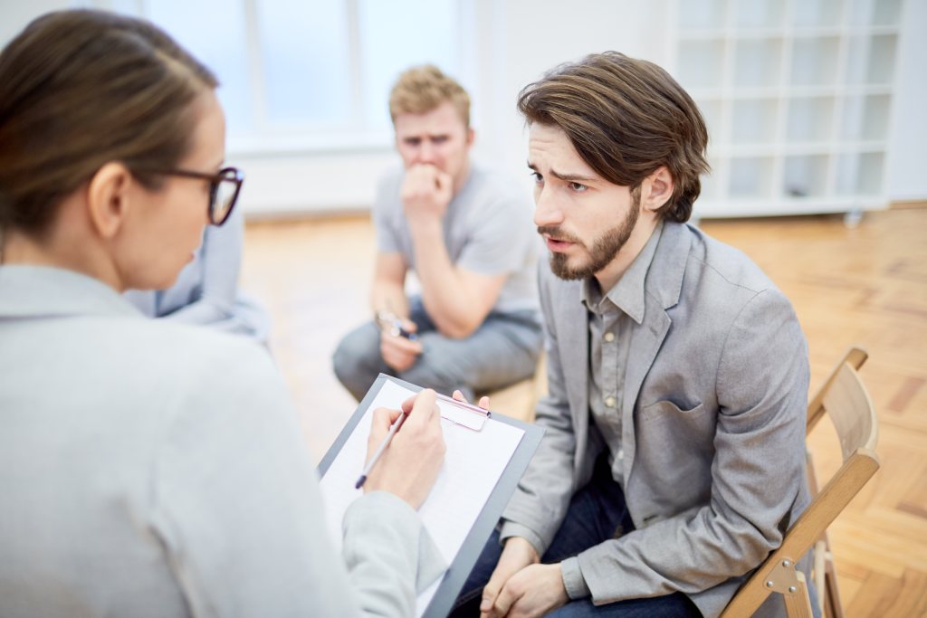 Can therapists diagnose? Troubled businessman explaining his problem to counselor during group session