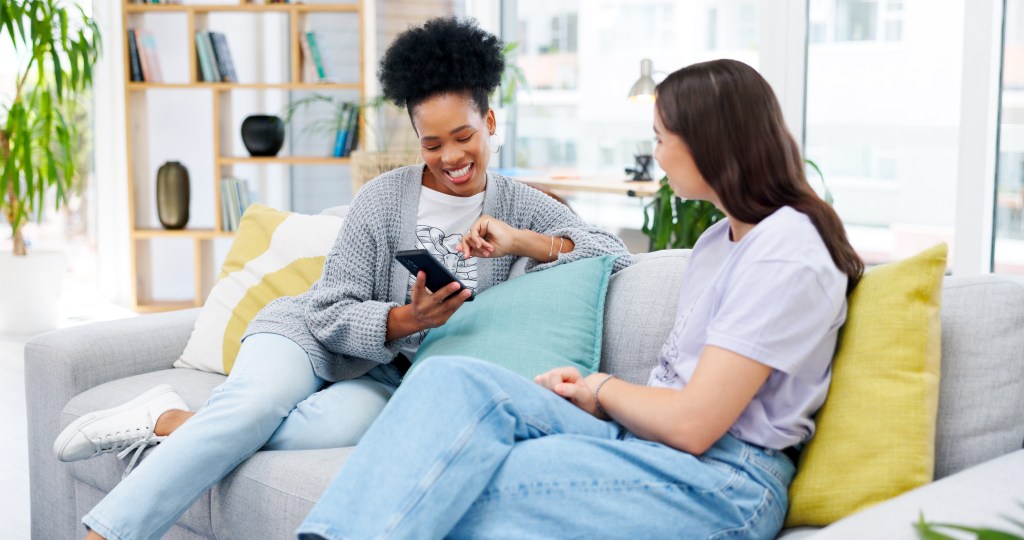 Friends chatting with an AI therapist app, sitting on sofa in living room