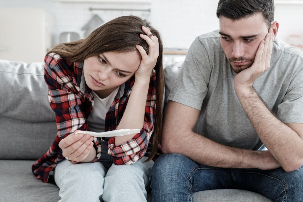How to tell your parents you're pregnant when they won't be happy: Young couple worried because of positive pregnancy test