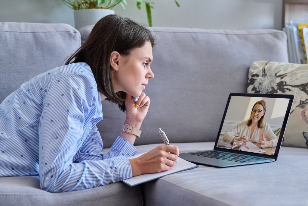 Emotional side of ADHD: Female lying on couch at home talking with therapist, taking notes