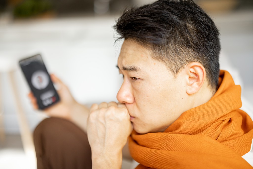 Overwhelmed, depressed man talking to a mental health professional via smartphone