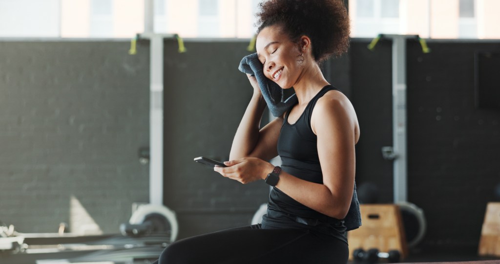 Woman, gym and happy with her AI coach on her smartphone 