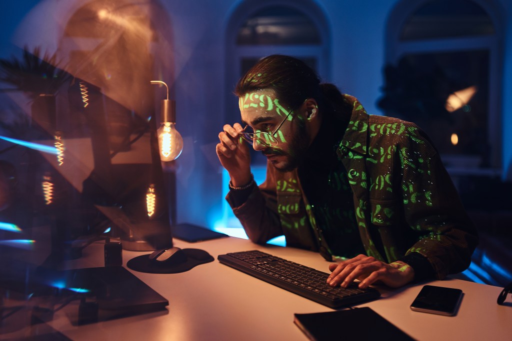 AI psychosis? Computer specialist seeing things in the code that don't exist while working late in dark office room.