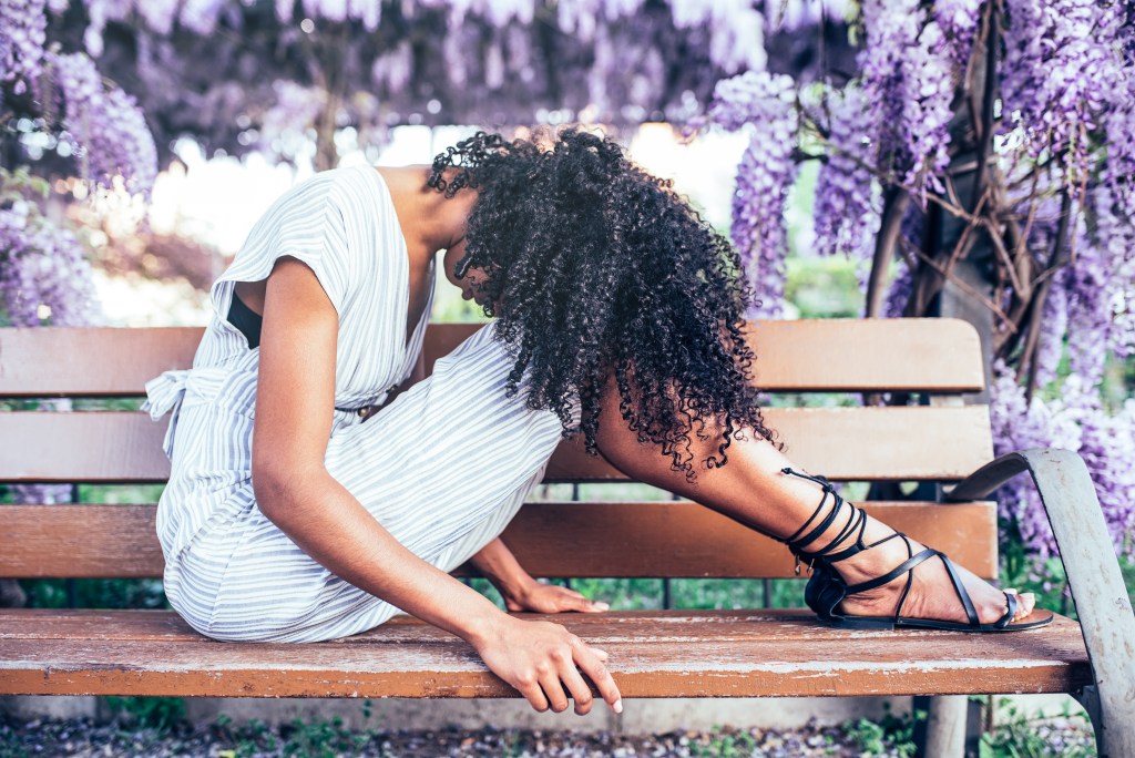 Healing from trauma quotes is not linear: Woman sitting on bench surrounded by flowers