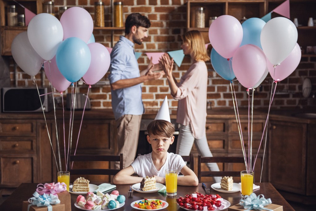 Divorced parents wars: fight on boy's birthday. He is looking angry, sad and frustrated amidst beautiful birthday decoration.
