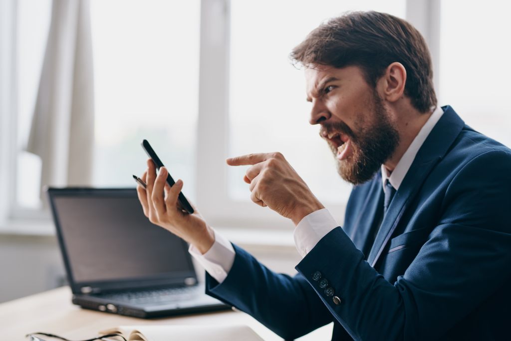 Emotional numbing? Man in blue business suit angrily talking into a smartphone
