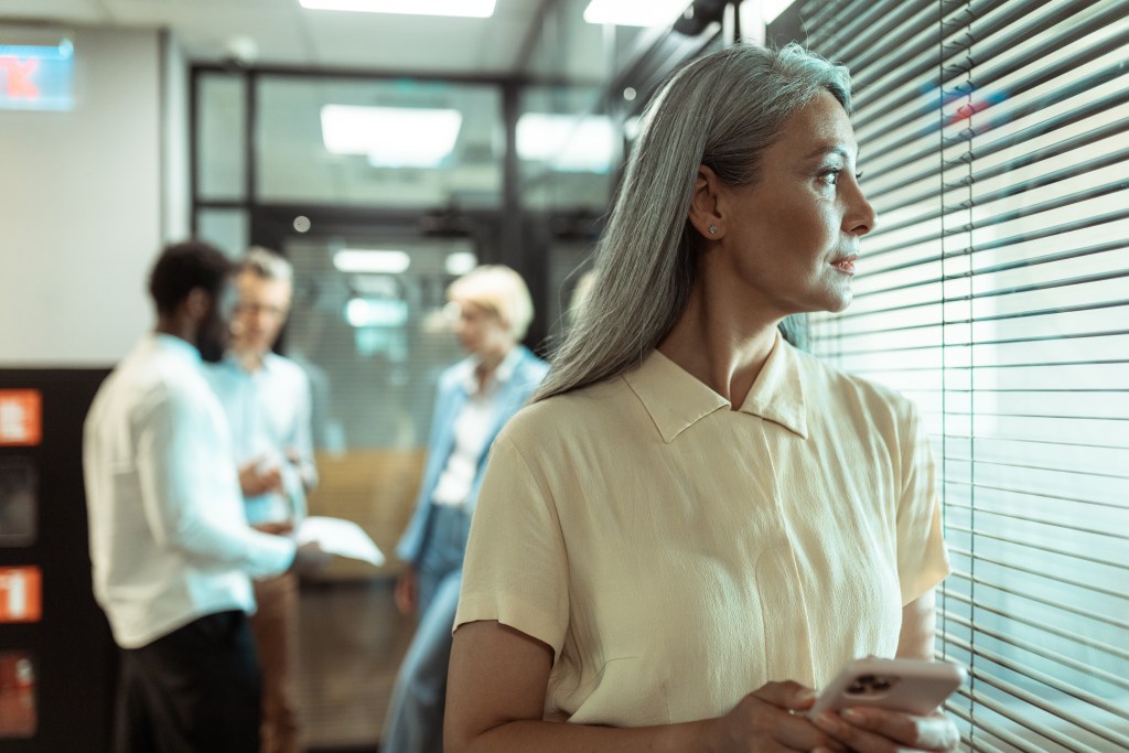 Senior professional looking out the window, experiencing friendship anxiety due to lack of clear signals