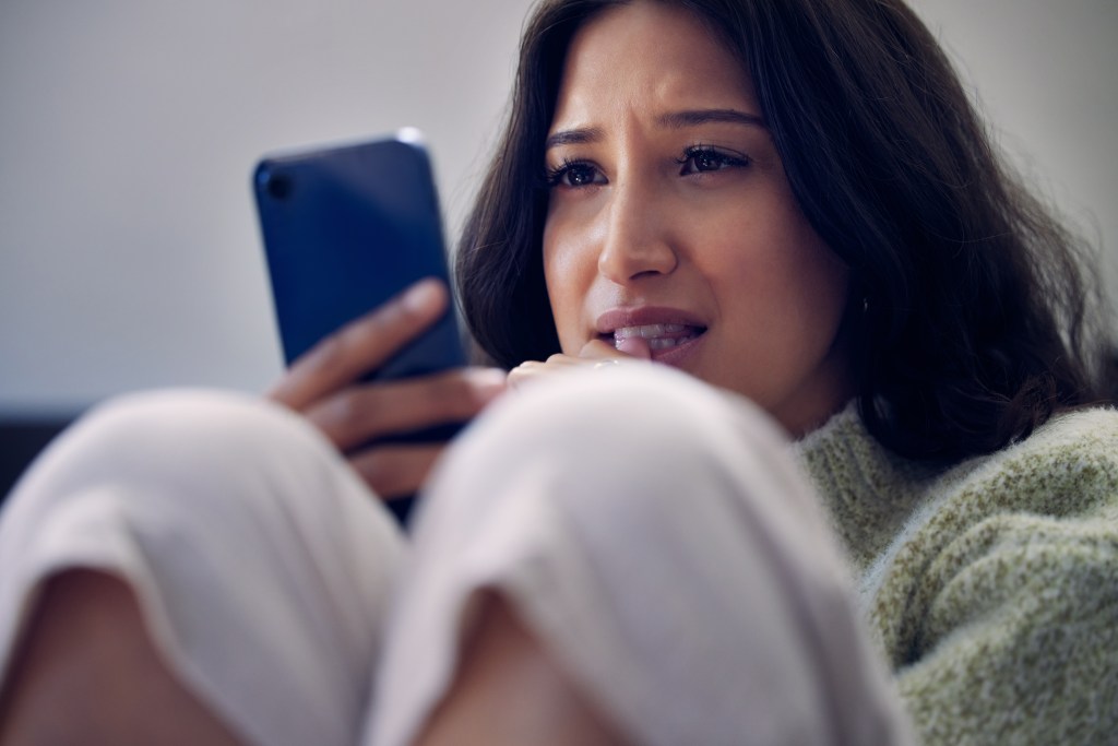 Woman looking at her phone, suffering due to friendship anxiety from fake friends