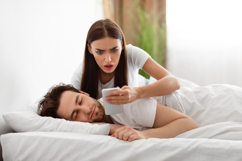 Intuition or anxiety?  Woman checking her husband's phone while he's sleeping
