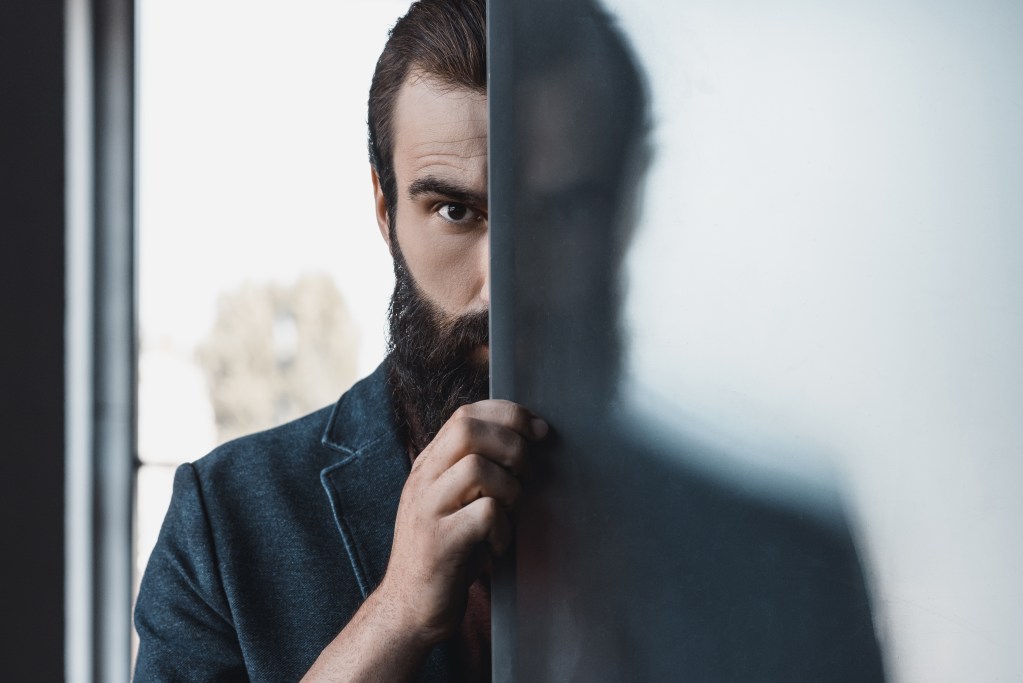 Intuition or anxiety?  Man hiding by frosted glass, observing the scene