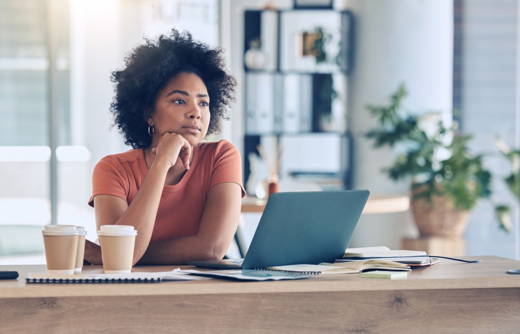 Should I quit my job? Woman in office, reflecting on draining frustrating work