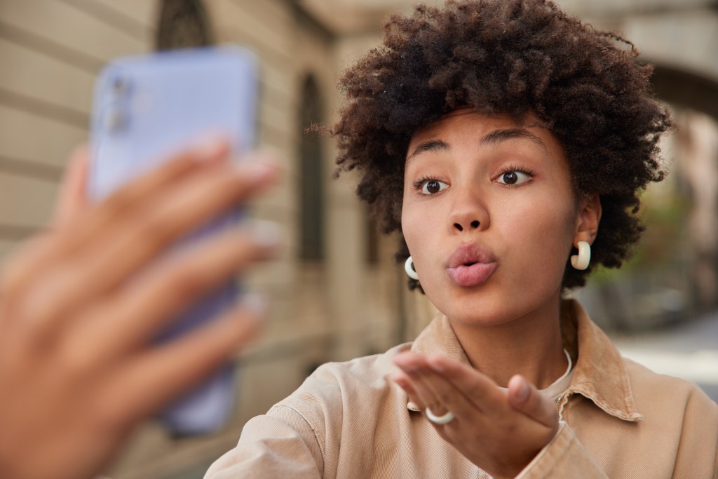 Front view of a woman blowing a kiss to her AI boyfriend