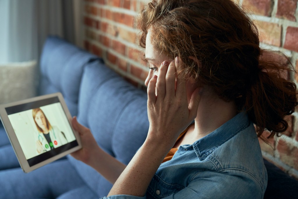 AI therapy or traditional therapy? Woman having an online session with a human therapist from the comfort of her couch.