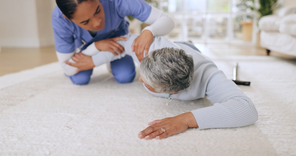 Medical alert system: Nurse helping senior after fall in living room