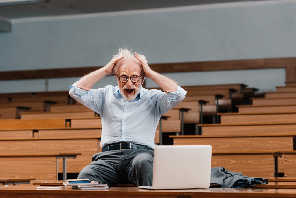 School stress: Senior lecturer in empty lecture room screaming and looking at camera