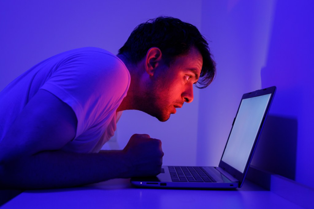 Parasocial meaning: Man obsessing with something behind his laptopscreen