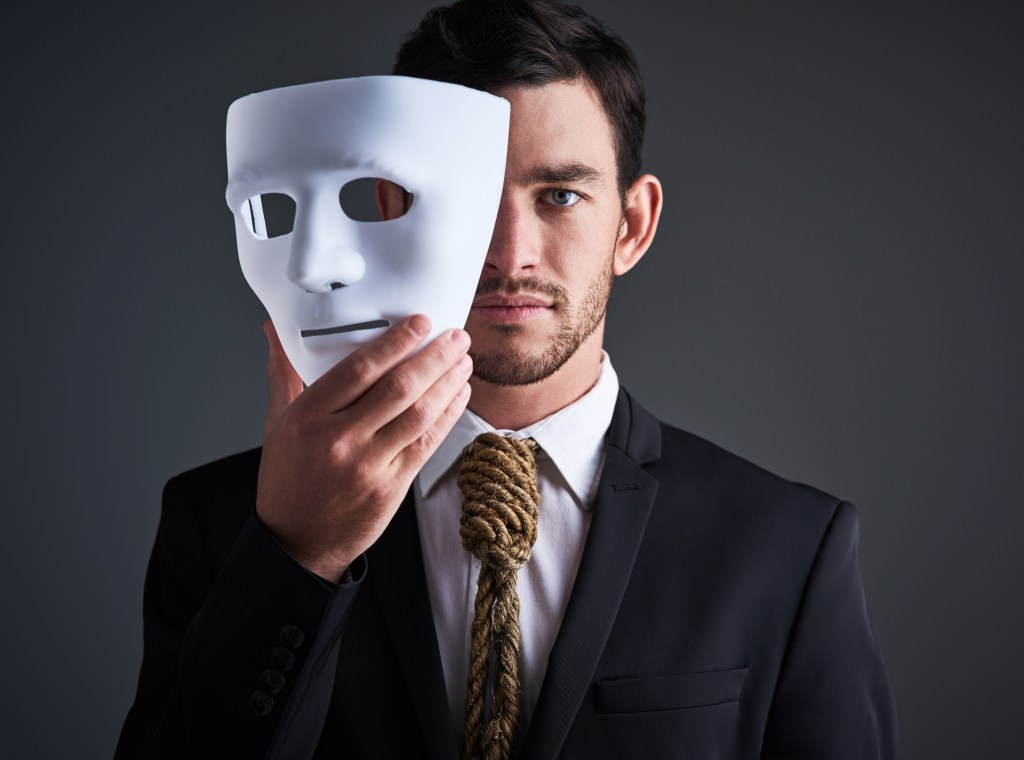 Accepting help is hard: Business man holding a white mask in front of his face, a noose around his neck that symbolizes how tied up he is in his impostor syndrome