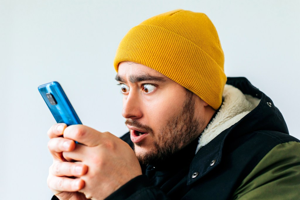 Bearded man staring at his phone which he has a toxic relationship with