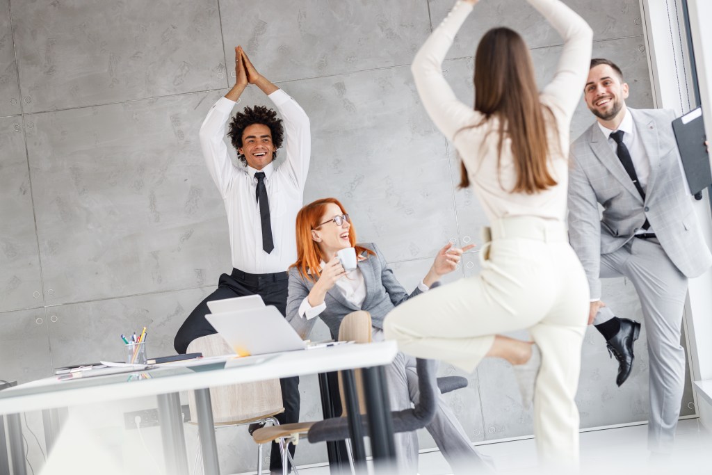 Group of office workers having fun together while decompressing with easy mobility exercises 