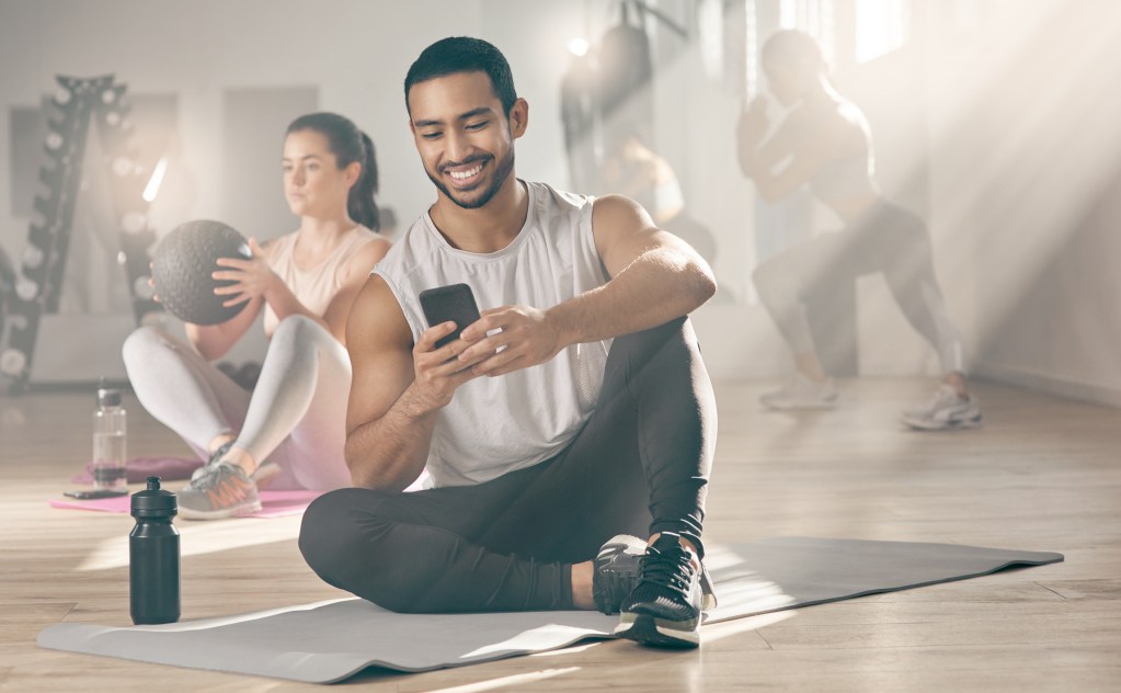 Burnout survivor turned fitness app founder looking at phone in gym